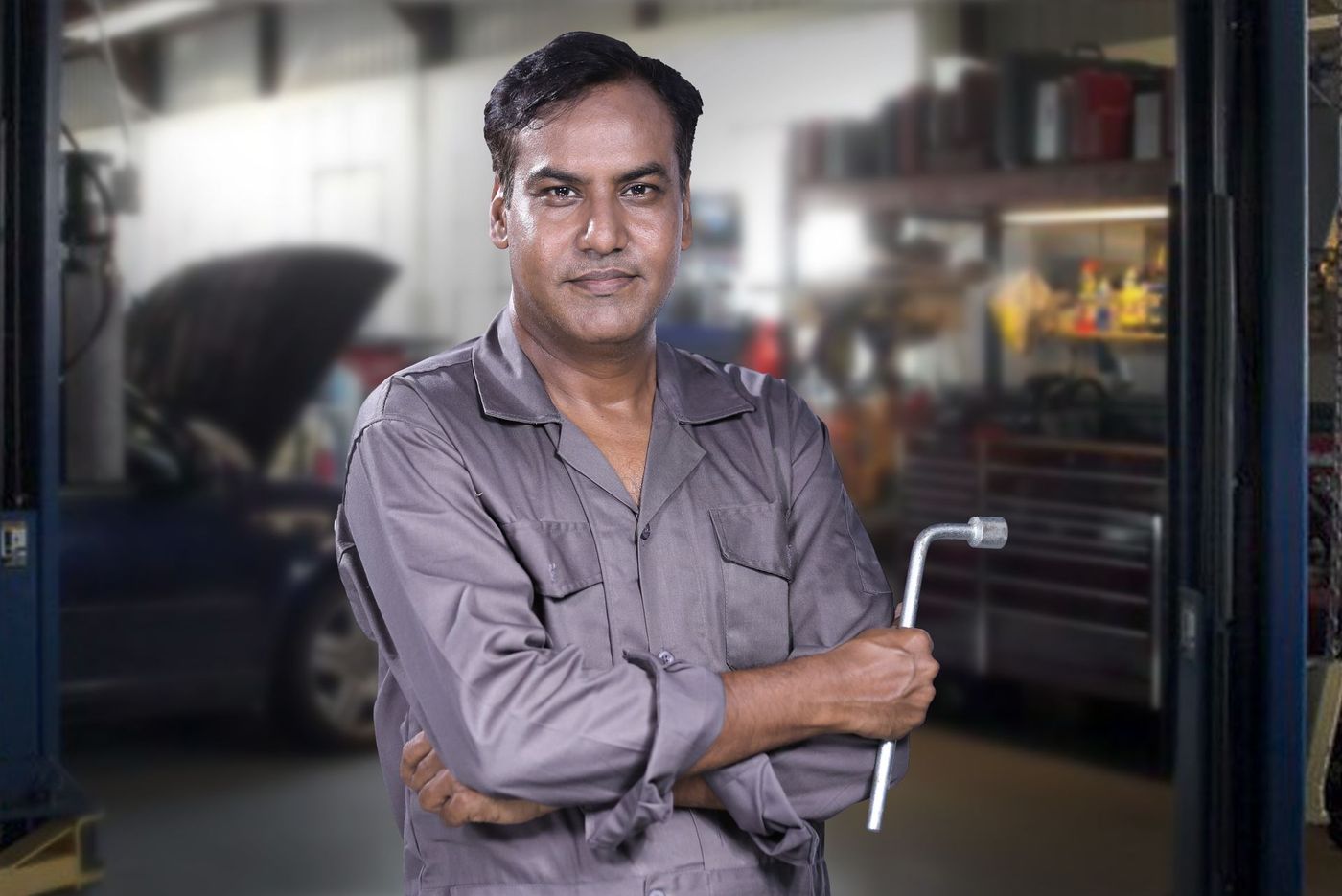 A technician in a plain grey work shirt holding a lug wrench